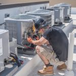 HVAC technician in New York inspecting rooftop air conditioning units for maintenance or repair.